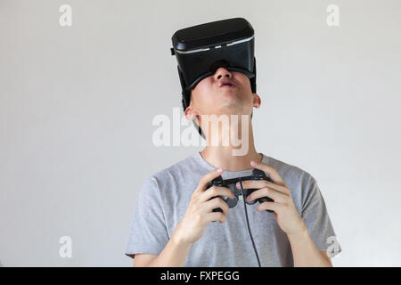 Asian man wearing VR goggle and immersing himself in VR gaming in white isolated Stock Photo