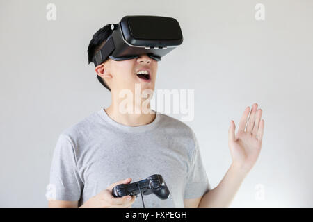 Asian man wearing VR goggle and immersing himself in VR gaming in white isolated Stock Photo