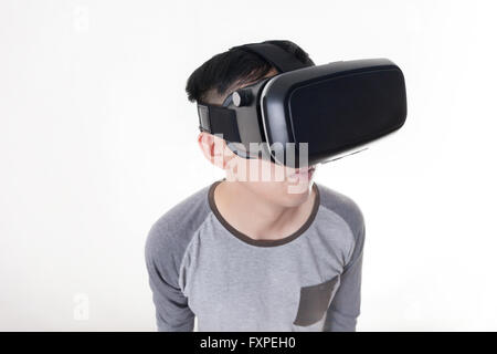 Asian man wearing VR goggle and immersing himself in VR multimedia in white isolated. Stock Photo