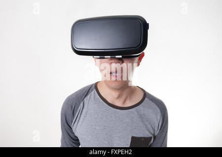 Asian man wearing VR goggle and immersing himself in VR multimedia in white isolated. Stock Photo