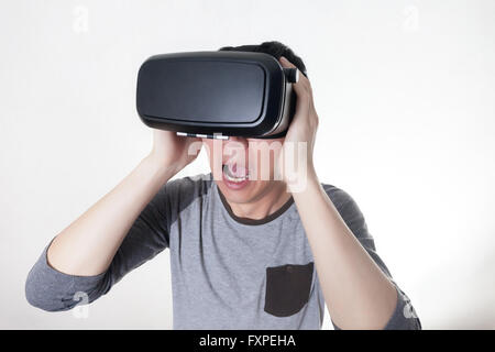 Asian man wearing VR goggle and immersing himself in VR multimedia in white isolated. VR stands for Virtual Reality Stock Photo
