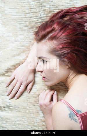 Worried redhead woman in bed Stock Photo