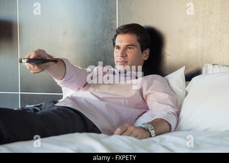 Man lying on bed, watching TV Stock Photo