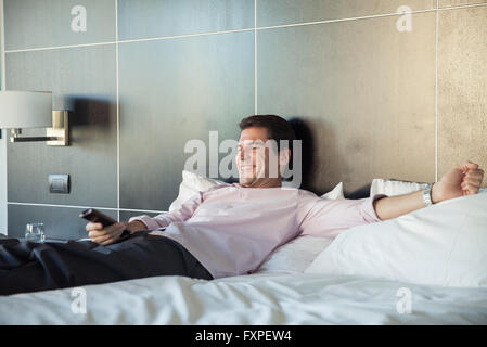 Man lying on bed, watching TV Stock Photo