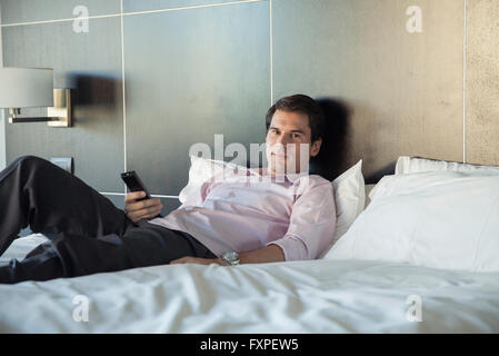 Man unwinding after work by watching TV on bed Stock Photo