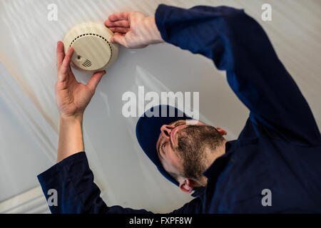 Handyman installing smoke detector Stock Photo