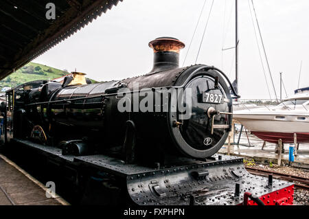 The restored steam locomotive Lydham Manor stands gleaming at the platform of Kingswear Railway Station on a damp misty day Stock Photo