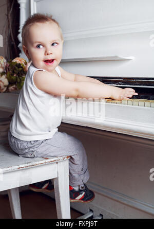 one year old baby boy playing an old piano Stock Photo