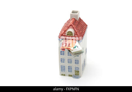 A money box in the shape of a house filled with money Stock Photo