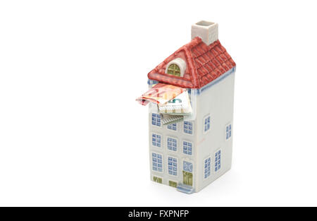A money box in the shape of a house filled with money Stock Photo