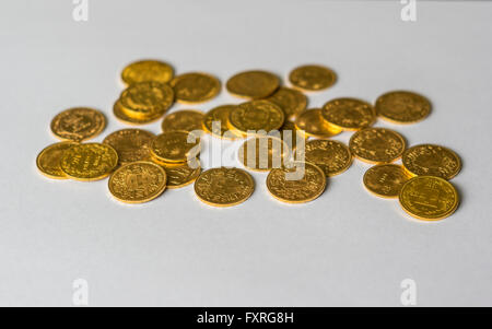 Several dozen gold coins, mostly 19th century 20 Francs coins from Switzerland, piled up on white background Stock Photo