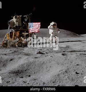 NASA astronaut and Apollo 16 commander John W. Young leaps from the lunar surface as he salutes the United States flag at the Descartes landing site during the first EVA mission April 21, 1972. The lunar module Orion and the Lunar Roving Vehicle are left of Young. Stock Photo