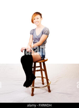 Smiling Asian American Woman Sitting On Stool Stock Photo