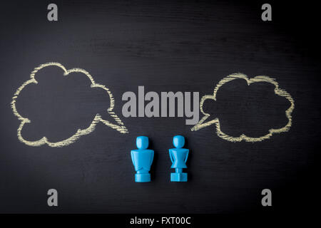 Male and female figurines on black chalkboard with hand drawn speech bubbles . Relationship and communicatioin concept. Stock Photo