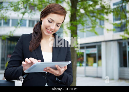 Attractive business woman using tablet computer on the way in the city Stock Photo