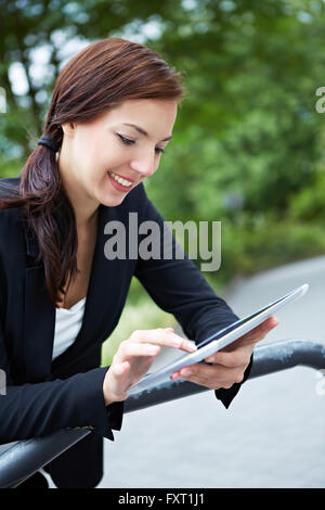 Businesswoman on the way working with tablet computer in a park Stock Photo