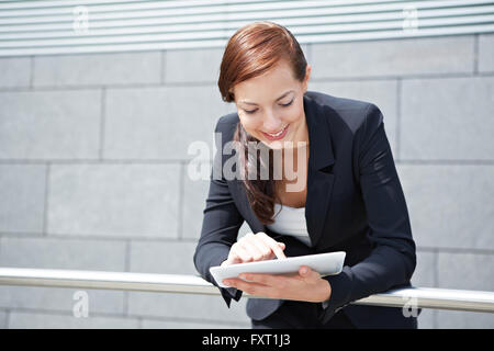 Attractive smiling businesswoman with tablet computer on the way Stock Photo