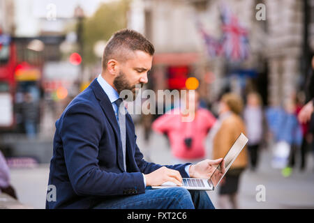 Hipster manager working on laptop on Piccadilly Circus, London Stock Photo