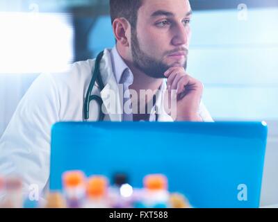 Doctor thinking about patient medical test results, samples in foreground Stock Photo