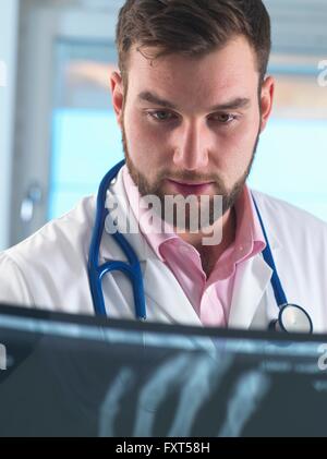 Young male junior doctor examining x-ray of fractured hand in hospital Stock Photo