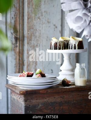 Mini christmas puddings with figs on stack of plates on patio table Stock Photo