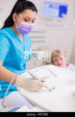 Dentist conducting dental treatment on girl in dental clinic Stock Photo