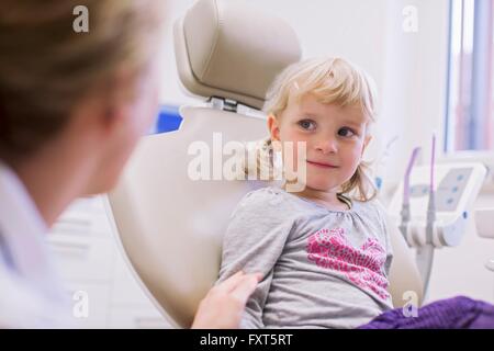 Worried looking girl in the dentist chair in front of the doctor is ...