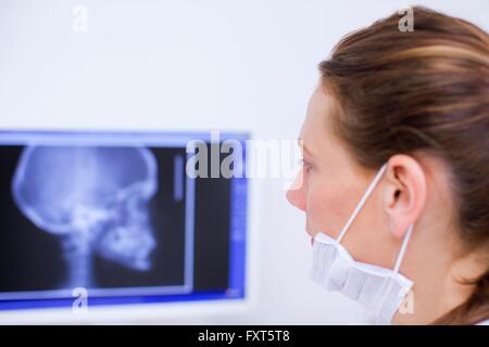 Side view of dentist looking at x-ray image on computer screen Stock Photo