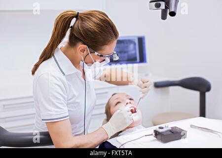 Dentist in dental clinic conducting dental examination on young woman Stock Photo