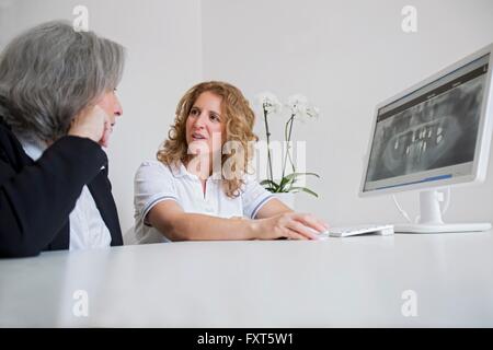 Surface level view of mature woman and senior woman discussing x-ray image on computer screen Stock Photo