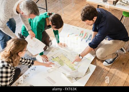 High angle view of architects discussing blueprints on wooden floor Stock Photo