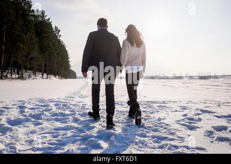 Young couple walking on snow-covered field Stock Photo