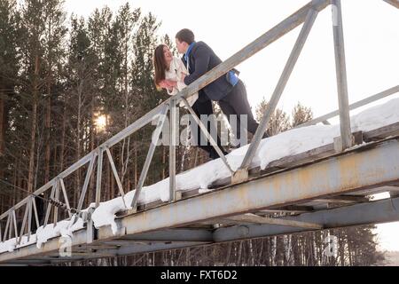 Young couple chatting, leaning on bridge railing Stock Photo