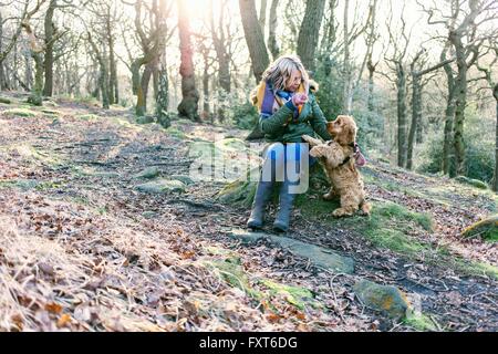 Woman giving treat to puppy in forest
