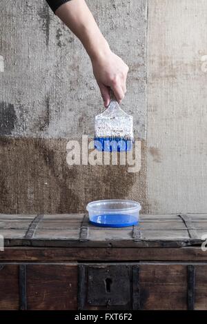 Hand holding paint brush over plastic container Stock Photo