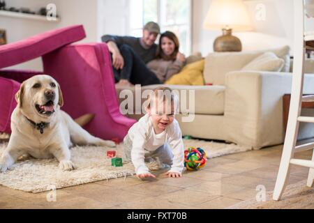 Baby boy and pet dog playing in fort made from sofa cushions Stock Photo