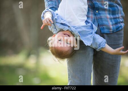 Low section of father hanging smiling baby boy upside down Stock Photo