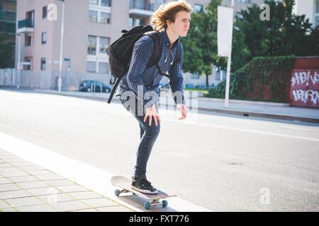 Young male skateboarder skateboarding along sidewalk Stock Photo