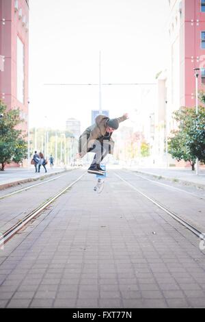 Young male skateboarder doing skateboarding jump on tramway Stock Photo