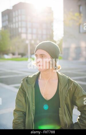 Cool young man wearing knitted hat standing near tower block Stock Photo