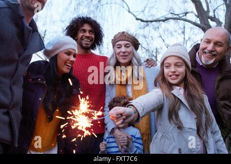 Girl with multi generation family holding sparkler smiling