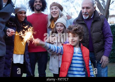 Boy with multi generation family holding sparkler smiling