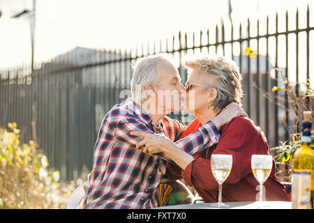 Romantic senior couple on city rooftop garden kissing