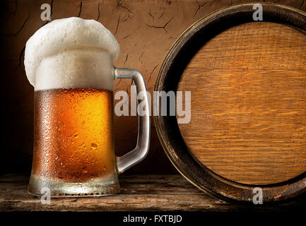 Frothy beer and wooden barrel in clay cellar Stock Photo