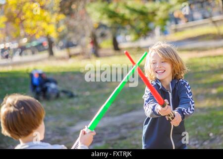 Two young brothers, play fighting with laser swords Stock Photo