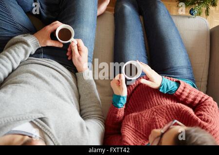 Overhead view of couple sitting on sofa holding coffee cup Stock Photo
