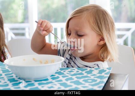 Girl eating breakfast from bowl with spoon Stock Photo