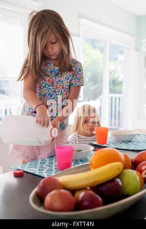 Girl pouring milk into plastic cup Stock Photo