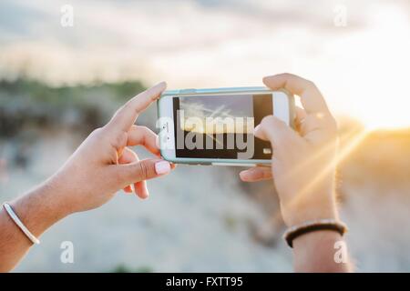 Womans hands using smartphone to photograph vapour trails Stock Photo