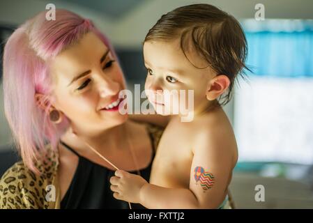Portrait of young woman with pink hair carrying baby son Stock Photo
